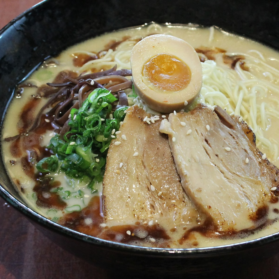Close-up of Huntington Ramen & Sushi's ramen bowl with pork, egg, noodles, and green onions.