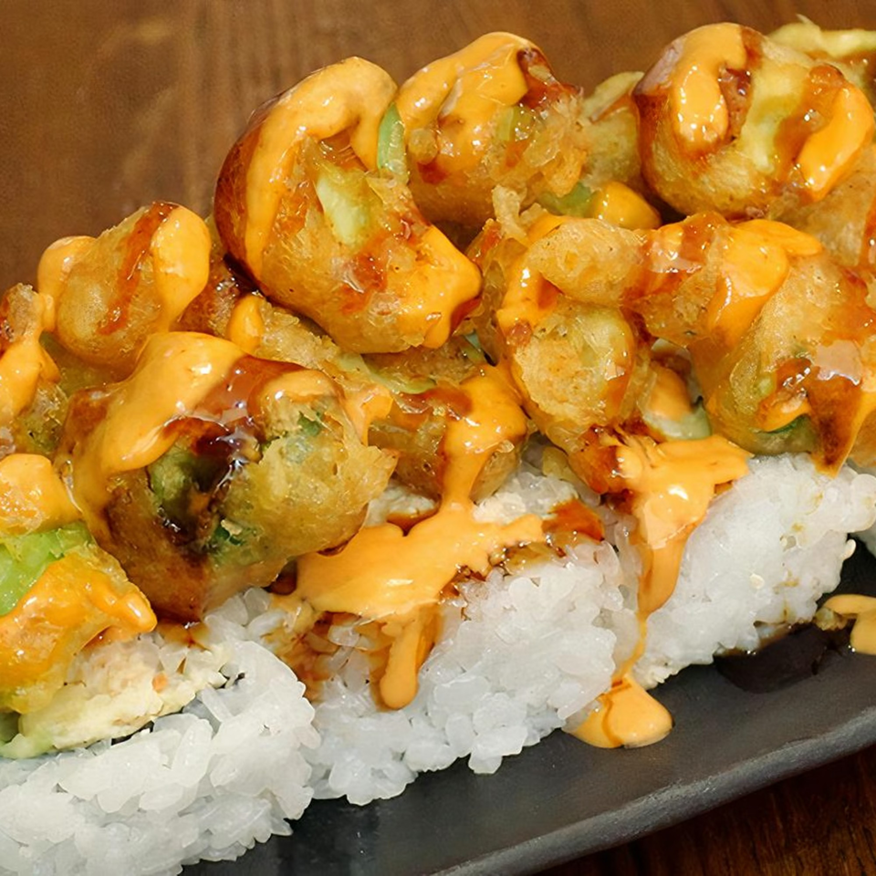 Close-up of Huntington Ramen & Sushi's fried sushi roll topped with orange and brown sauces.